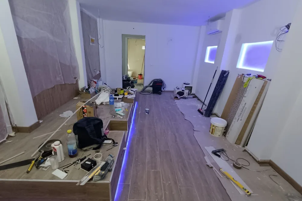 Local comercial durante la obra, con el mostrador montado y materiales en el suelo